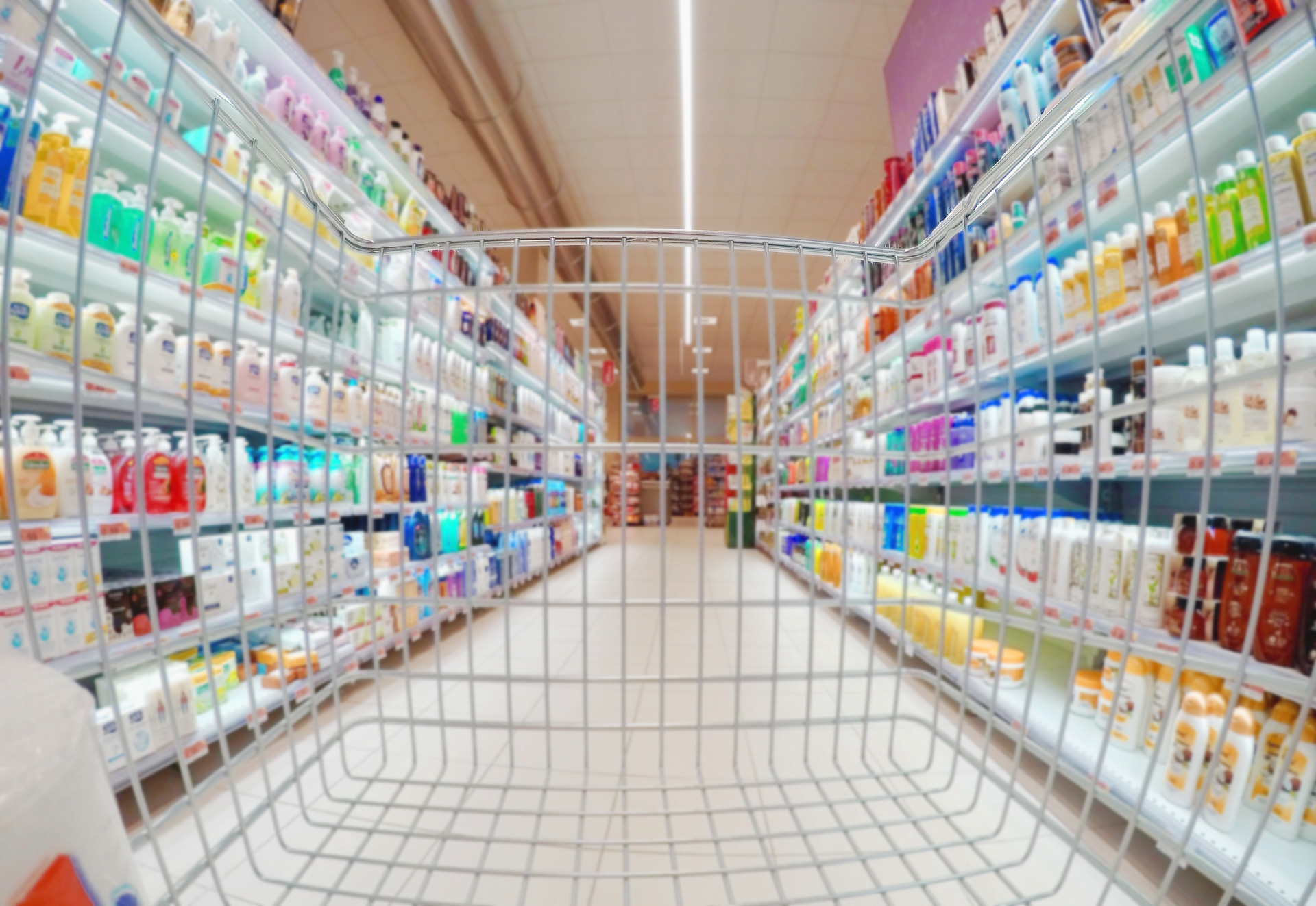 Empty shopping cart between shelves full of products